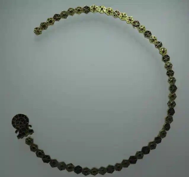 A cross at one end of a gold necklace, decorated with red stones